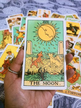 A close-up of The Moon tarot card held in hand, ideal for spiritual themes.